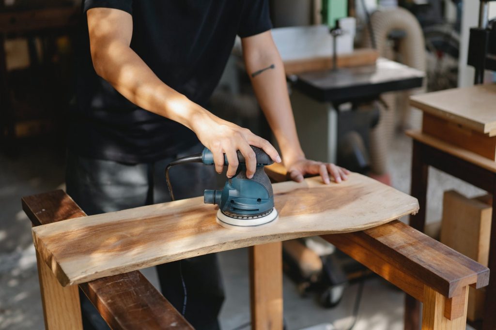 Image of Craftsman polishing wooden board with grinding instrument