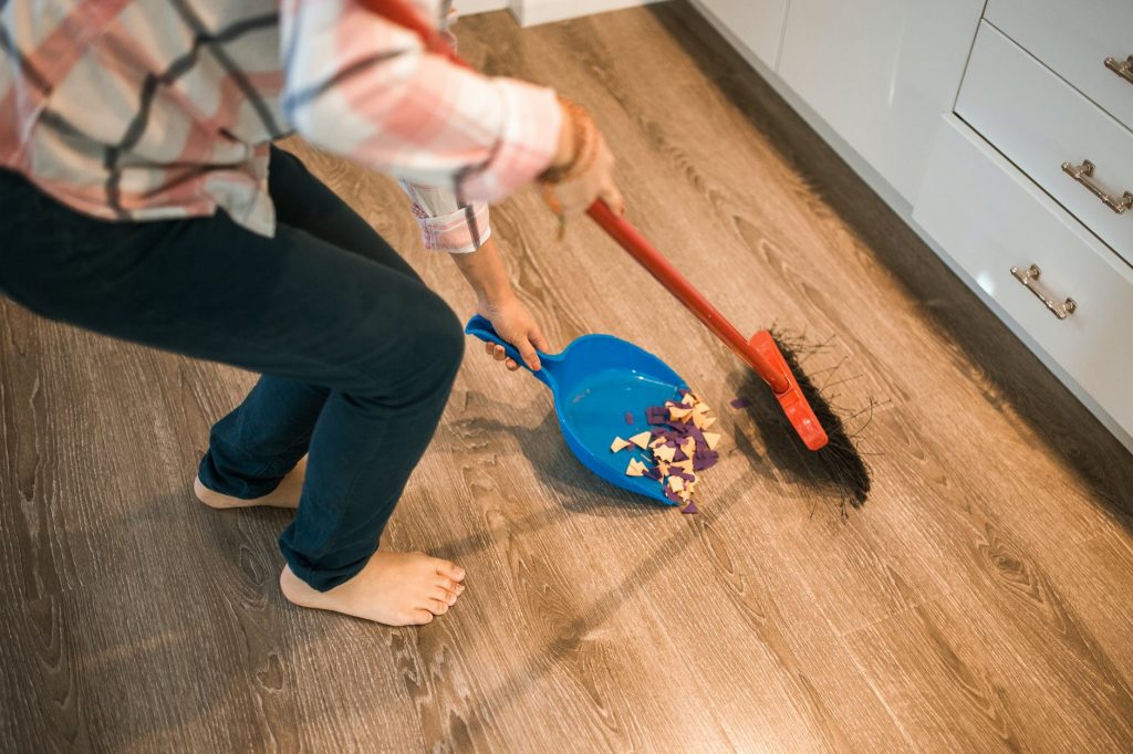 Image of Person in White and Red Long Sleeve Shirt and Blue Pants Holding Blue Plastic Fly Swatter