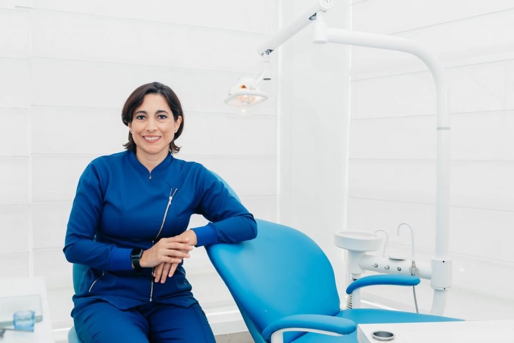 Image of Woman in Blue Attire Sitting Beside Dental Chair