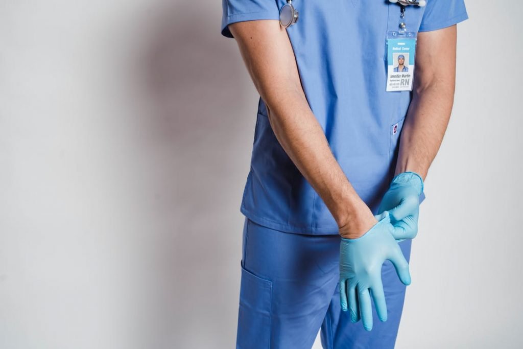 Image of Male doctor putting on sterile gloves