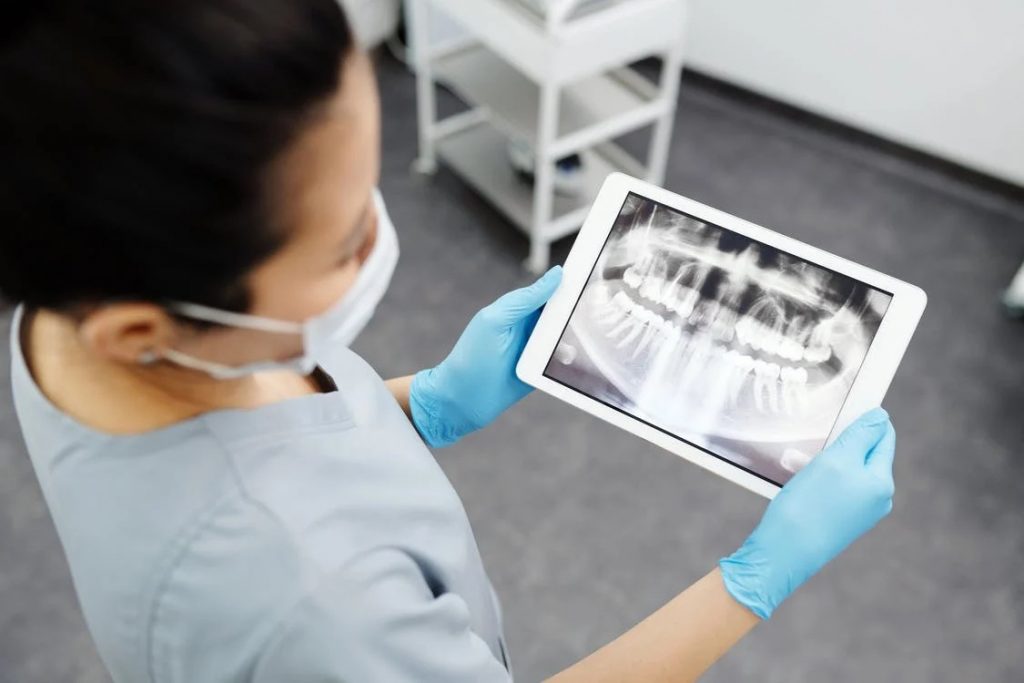 Image of A Person in Gray Scrub Suit Holding White Digital Tablet